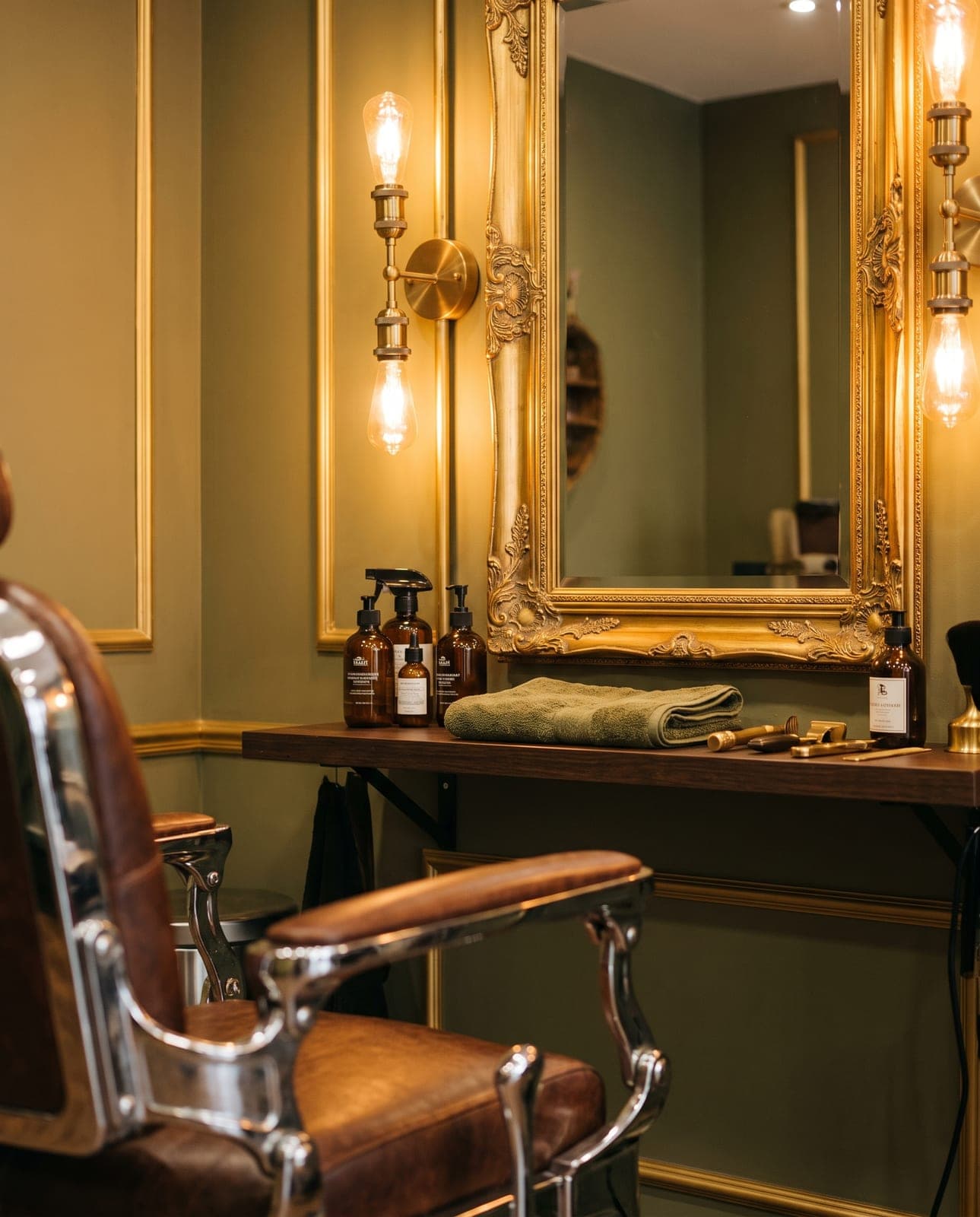A classic barber station at S & N Styling Center — a vintage leather chair, gilded mirror, olive walls and a folded towel in Charlotte, NC